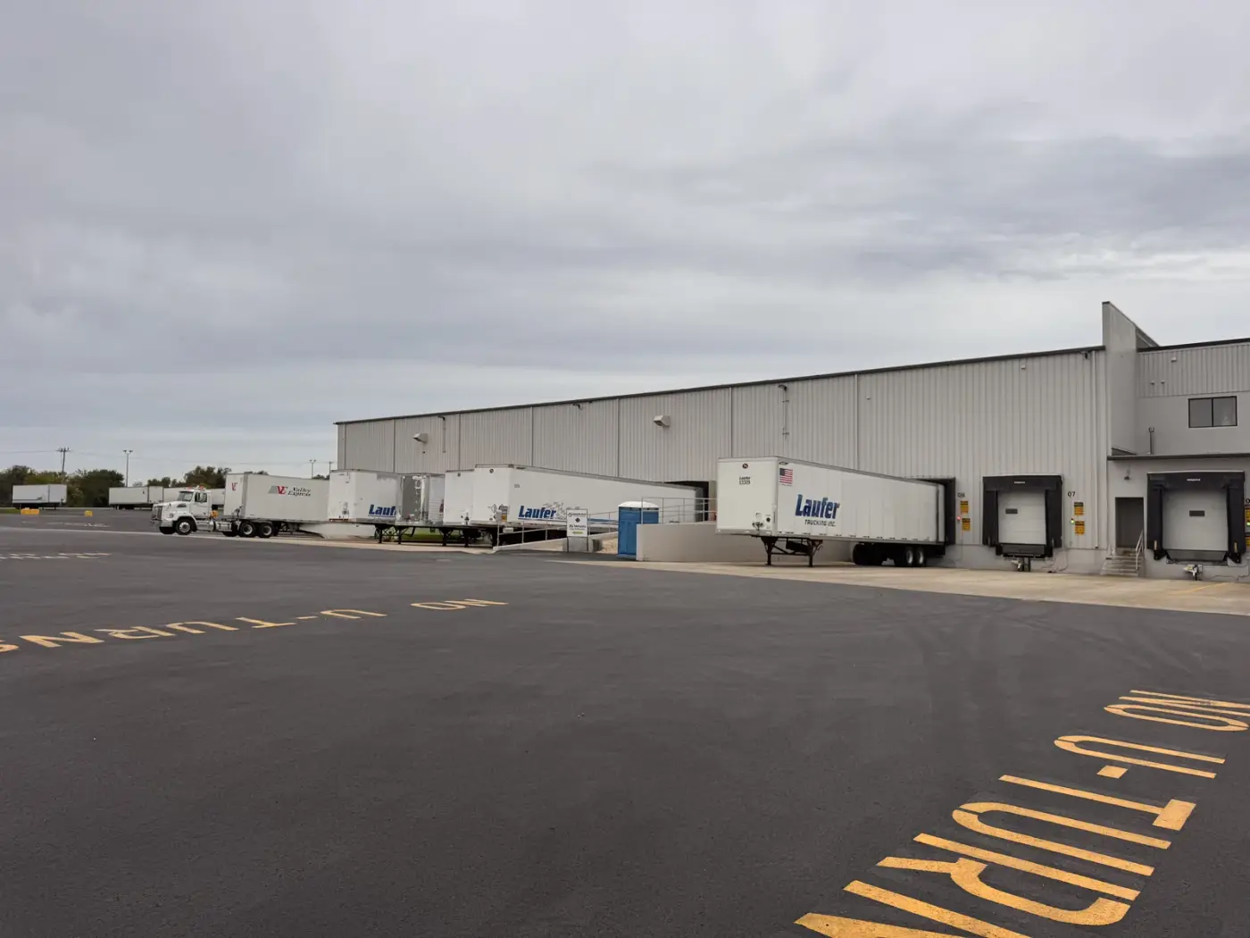 Laufer Trucking dry van trailers parked at warehouse loading docks for drop and hook freight operations.
