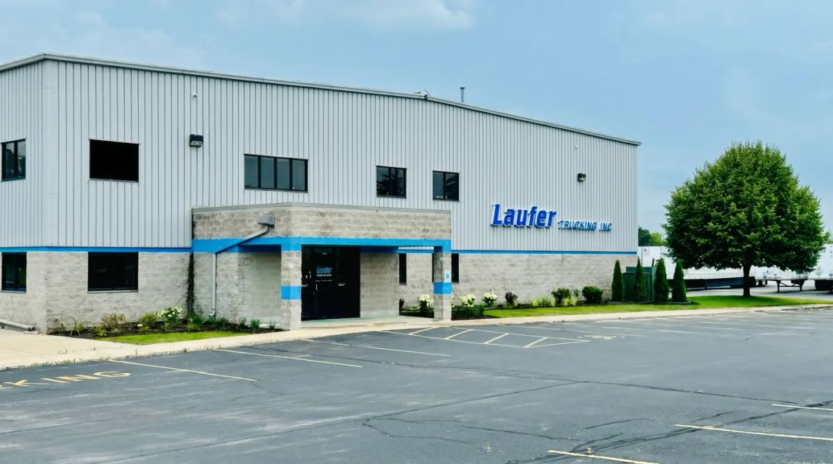 The exterior of the Laufer Trucking headquarters and warehouse featuring a modern metal and stone facade with blue company signage.