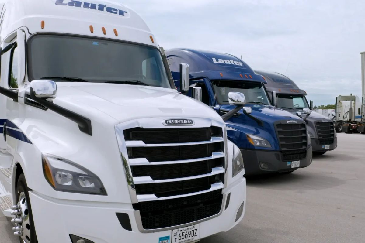 A row of white and blue Laufer Trucking semi-trucks parked at a fleet facility in Wisconsin.